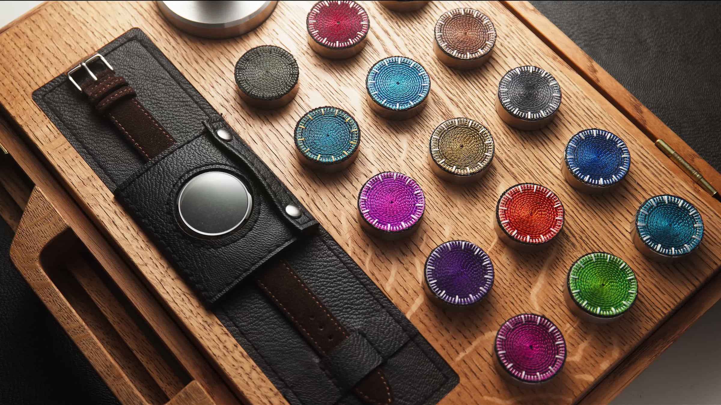 Chenille-embroidered watch dials in the studio's wooden tray, ready for casing