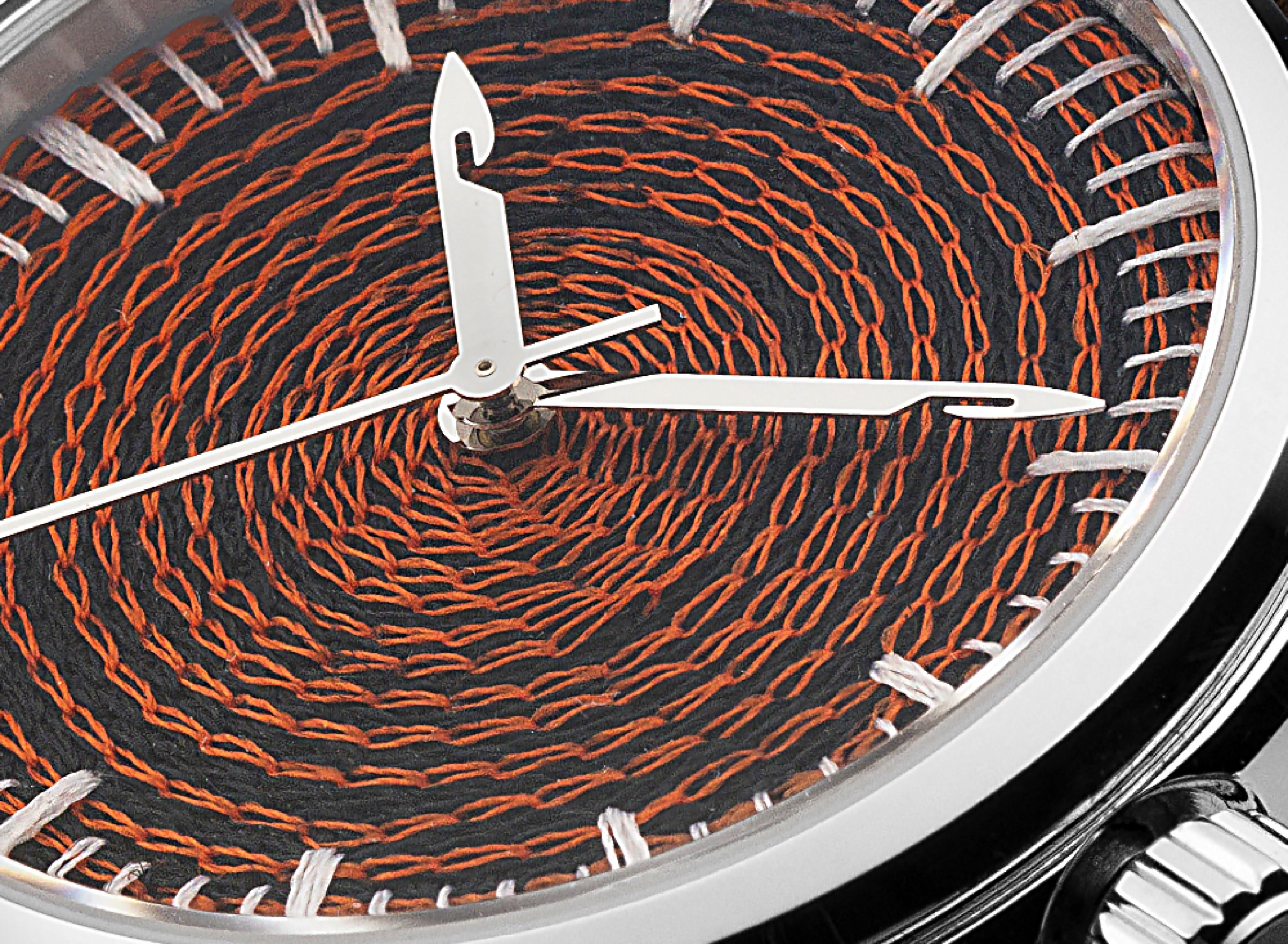 Extreme macro of chenille-embroidered watch dial, rust-orange thread against black