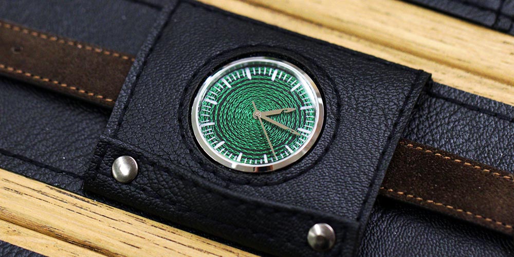 CORNELY watch resting in an open leather case on wood, forest green chenille dial seen from above