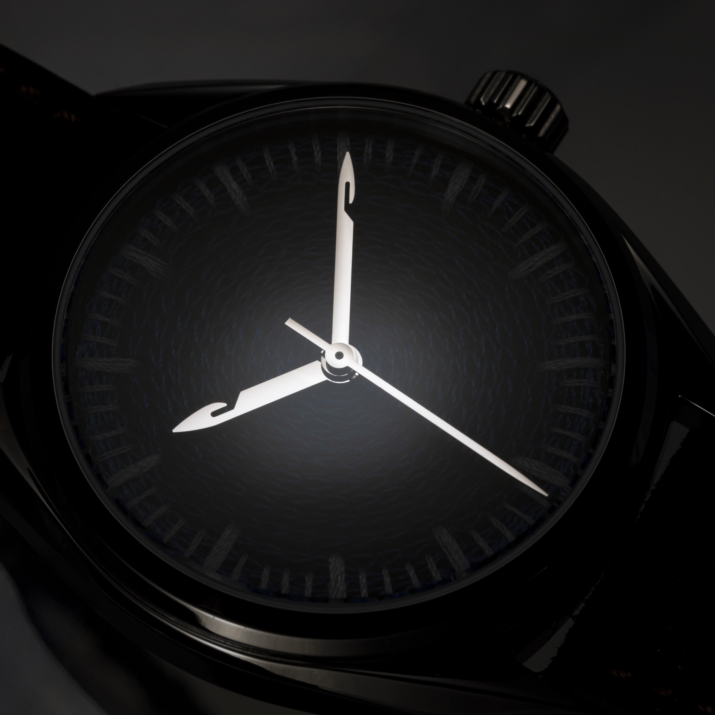 Macro of a chenille-embroidered watch dial in dramatic low light