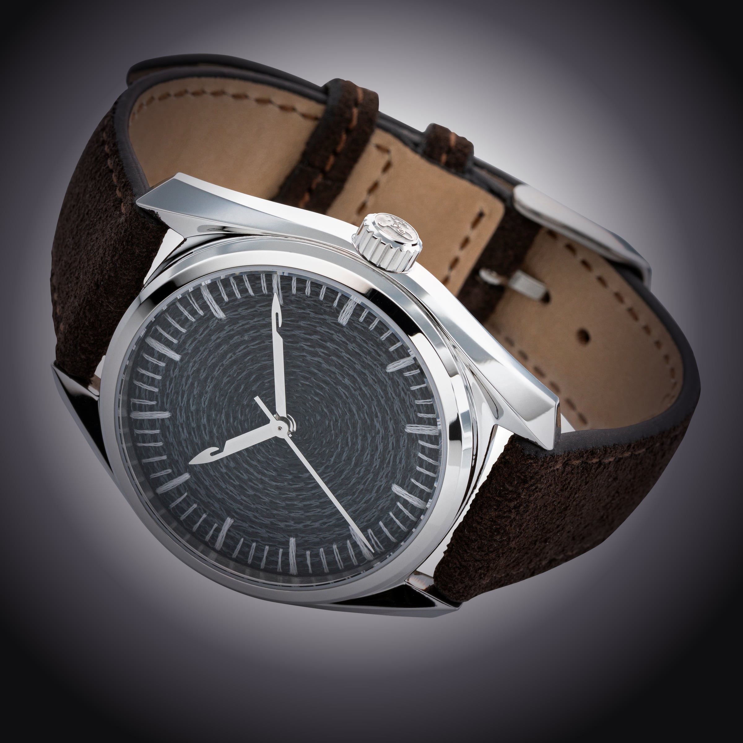 Three-quarter studio shot of the CORNELY watch, full case and strap, charcoal chenille dial, dark vignette